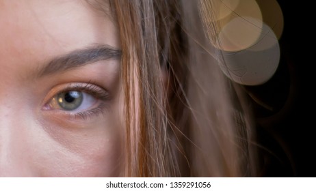 Closeup half-face portrait of young attractive caucasian female with brunette hair looking straight at camera with bokeh background - Shutterstock ID 1359291056