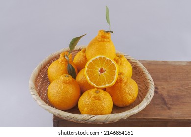 Close-up Of Hallabong Mandarin Fruits With One Cut In Half On A Bamboo Basket, Tree, Cutting Board, South Korea
