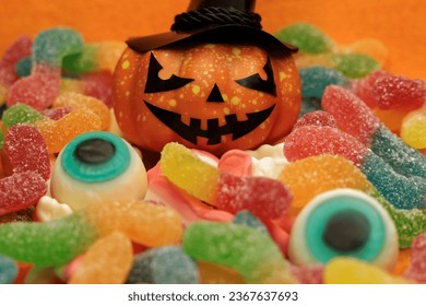 Close-up of a Halloween pumpkin with Jack mask and hat on a background of colorful jelly sweets - Shutterstock ID 2367637693
