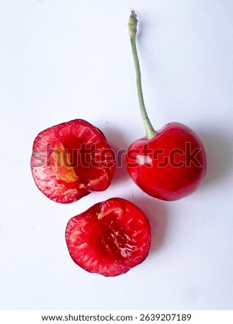 Close-up of a halved cherry with pit and part of a whole cherry next to it. Rich red texture, juicy and fresh, isolated on white background — ideal for food or health-themed visuals.
