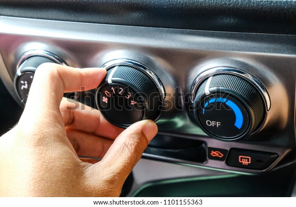 Closeup of hand adjust the air button in the\
car.Black air conditioning\
system.