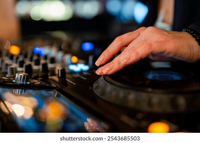 Close-up of a DJ’s hand adjusting equipment with colorful lights in the background, capturing the energy of live music mixing. Perfect for themes of nightlife, music events, and entertainment. - Powered by Shutterstock