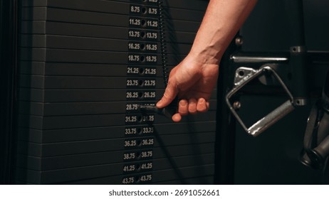 Close-up of a hand adjusting weight stack on gym machine, representing strength training, fitness equipment, workout preparation, and motivation for a healthy active lifestyle and muscle building.