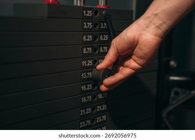 Close-up of a hand adjusting weight stack on gym machine, representing strength training, fitness equipment, workout preparation, and motivation for a healthy active lifestyle and muscle building.