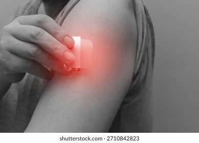 A close-up of a hand applying a nicotine patch to the upper arm. Represents Nicotine Replacement Therapy (NRT) and the user's commitment to quit smoking and pursue better health