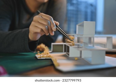 Close-up hand of Architect students diligently make house model building samples with paper art architecture tools at night in their alone room. - Powered by Shutterstock