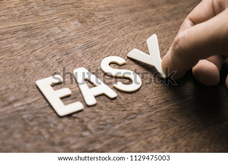 Closeup hand arrange wood letters as EASY word