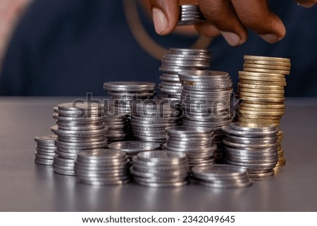 A close-up of a hand arranging a stack of coins in a variety of denominations