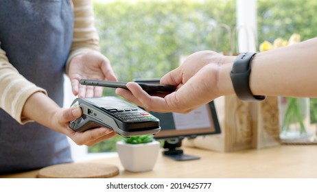Close-up hand asia woman people work in small sme coffee cafe shop store owner use cashless wifi qr code nfc scan app smart pos reader sale in take out food drink order in urban city life contactless.