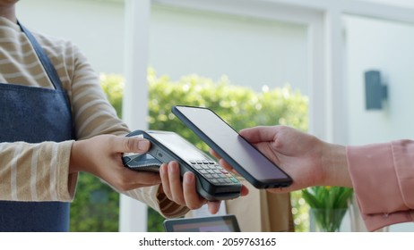 Close-up hand asia woman people work in small sme coffee cafe shop store owner use cashless wifi paywave nfc scan app smart pos reader sale in take out food drink order in urban city life contactless.