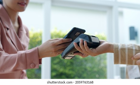 Close-up hand asia woman people work in small sme coffee cafe shop store owner use cashless wifi paywave nfc scan app smart pos reader sale in take out food drink order in urban city life contactless.