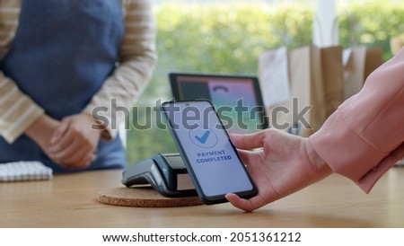 Close-up hand asia woman people work in small sme coffee cafe shop store owner use cashless wifi paywave nfc scan app smart pos reader sale in take out food drink order in urban city life contactless.