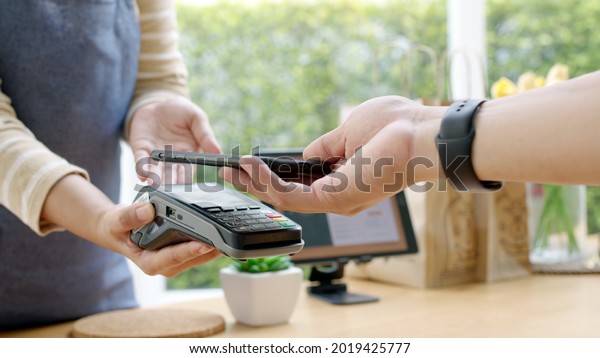 Close-up hand asia woman people work in\
small sme coffee cafe shop store owner use cashless wifi qr code\
nfc scan app smart pos reader sale in take out food drink order in\
urban city life\
contactless.