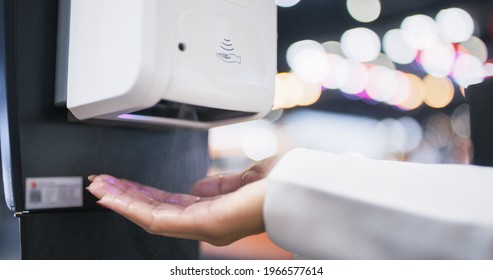 Close-up hand of Asian woman using hand sanitizer or alcohol gel dispenser, rubbing hand in public place. Clean healthy lifestyle, coronavirus prevention concept