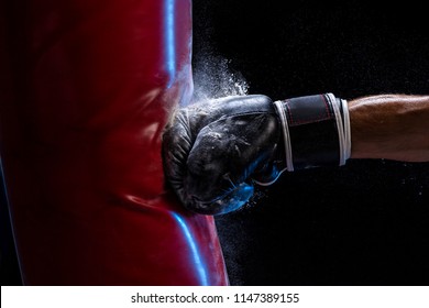Close-up hand of boxer at the moment of impact on punching bag over black background
