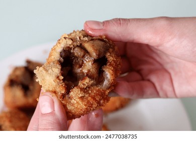 Close-up of a hand breaking open a crispy Japanese curry bun to reveal the succulent meaty filling inside