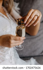 Nahaufnahme einer Braut mit einem Verlobungsring und einem Glas Champagner.