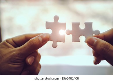 Closeup hand of business people connecting jigsaw puzzle with sunlight effect, Business solutions and represent team support and help concept, success and strategy concept