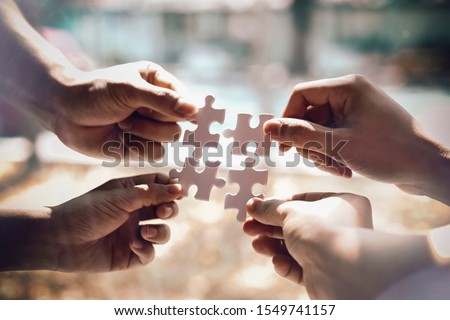 Closeup hand of business people connecting jigsaw puzzle with sunlight effect, Business solutions and represent team support and help concept, success and strategy concept

