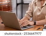 Closeup hand businesswoman using laptop computer on desk in living room at home office, business woman using laptop for surfing internet, entrepreneur or freelance, business and communication.