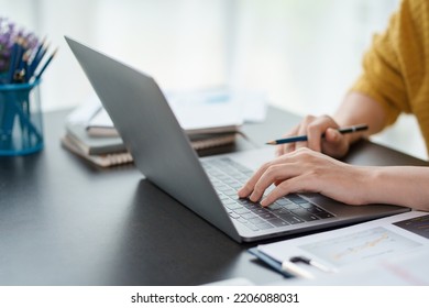Close-up of hand of businesswoman working together using laptop computer to record and print information for a marketing plan analyze the balance sheet report quarterly financial statement.