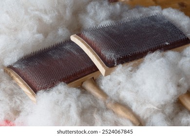 A close-up of hand carding tools surrounded by raw wool fibers - Powered by Shutterstock