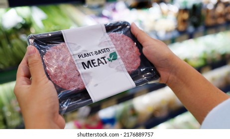 Close-up hand carry choose zero pork soy bean faux peas cutlet gluten free read beyond non-meat lab label. Buy raw fake beef tray in asia store veggie burger patty for health care eat diet meal cook. - Shutterstock ID 2176889757
