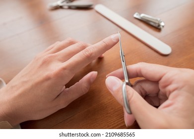 Close-up Of Hand Of Caucasian Young Woman Doing Manicure Scissors, Cut Nail At Home With Nail Supplies.