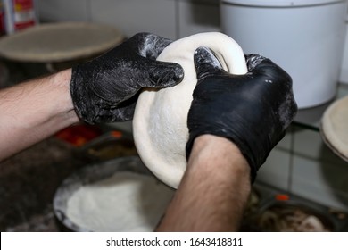Closeup Hand Of Chef Baker In Gloves Making Pizza At Kitchen.