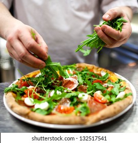 Closeup hand of chef baker in white uniform making pizza at kitchen