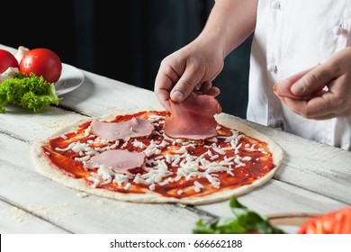 Closeup hand of chef baker in white uniform making pizza at kitchen: zdjęcie stockowe