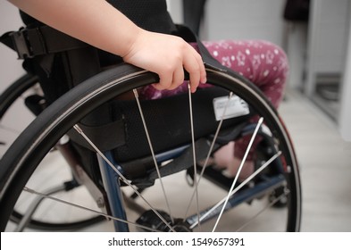 Close-up Hand Of A Child On A Wheel From A Wheelchair. Disabled Children Concept.