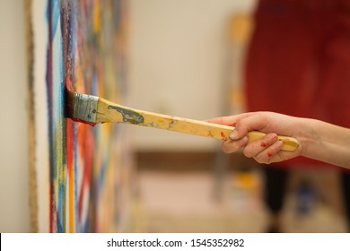 Closeup of the hand of a child painting a mural during an art lesson