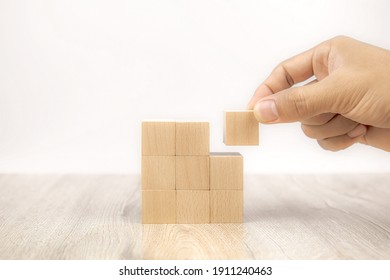 Close-up hand choose a cube shape wooden block toy stacked without graphics for Business design concept and activity for child foundation practice skills.
