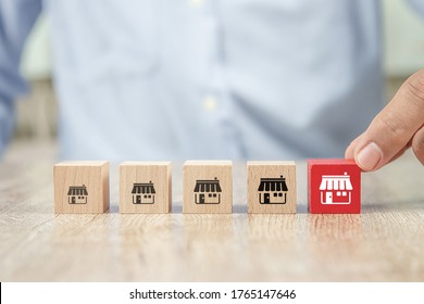 Close-up Hand Choose Cube Wooden Toy Blocks Place In Line Up With Franchise Business Store Icon. For Small Business Growth And  Branch Expansion Strategy Of Financial Marketing Planning.