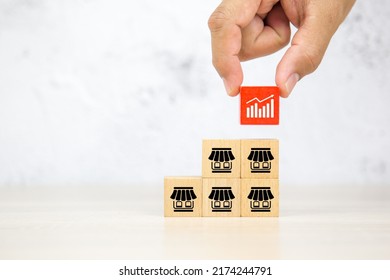 Close-up hand choose graph on wooden block stack pyramid with franchise business store icon for franchising to growth branch expansion and business banking loans.
