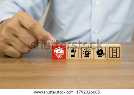Close-up hand choose prevent icon on cube wooden toy blocks stacked with fire exit prevention icon for fire safety protection concepts.