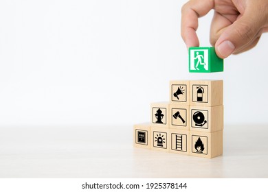 Close-up hand choose wooden toy blocks stacked with door exit sing icon with fire extinguisher and fire protection symbol for safety prevent and protect accident of emergency and rescue. - Shutterstock ID 1925378144