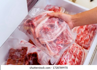 Closeup of hand choosing fresh raw ribs meat in the freezer - Shutterstock ID 1728789970