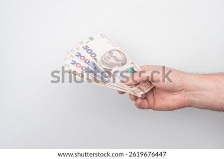 Close-up of a hand clutching Euro banknotes, including 500 euros bills and smaller denominations, under even lighting, indoor setting