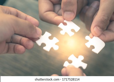 Closeup hand of diverse people connecting jigsaw puzzle which is a team work of the business detail blur