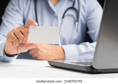 Close-up Of Hand A Doctor Holding A Blank White Paper Or Mockup Name Card While Sitting In The Office. Close-up Photo. Business Branding Concept