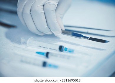 Closeup of hand, doctor and medical tools, scalpel and needle syringe for surgical procedure in healthcare. Medicine, health insurance and operation, surgeon person in hospital with clean instruments - Powered by Shutterstock