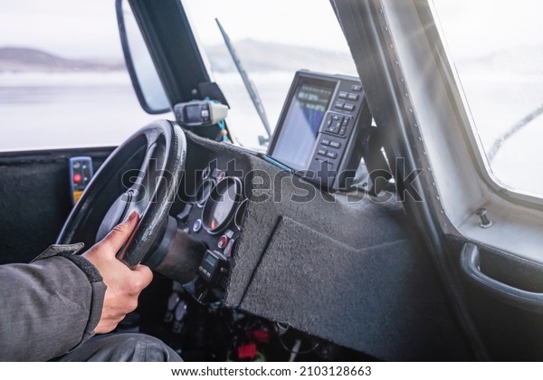 Close-up Hand of driver holding steering wheel\
while driving a hovercraft that moves on frozen lake Baikal, travel\
lifestyle concept