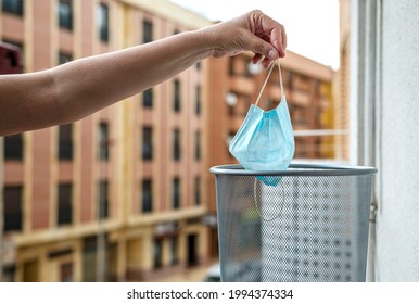 Close-up Of A Hand Dropping A Medical Mask Into A Waste Garbage Can, End-of-quarantine Concept	
