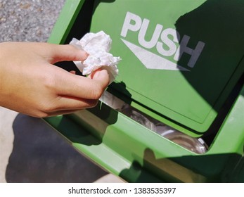 Close-up Hand Dropping Tissue Paper Into Green Plastic Trash Bin With Push Word On Lid