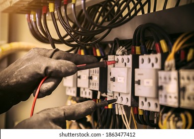 Close-up hand of electrical engineer using measuring equipment to checking electric current voltage at circuit breaker and cable wiring system for maintenance in main power distribution board. - Shutterstock ID 1863477412