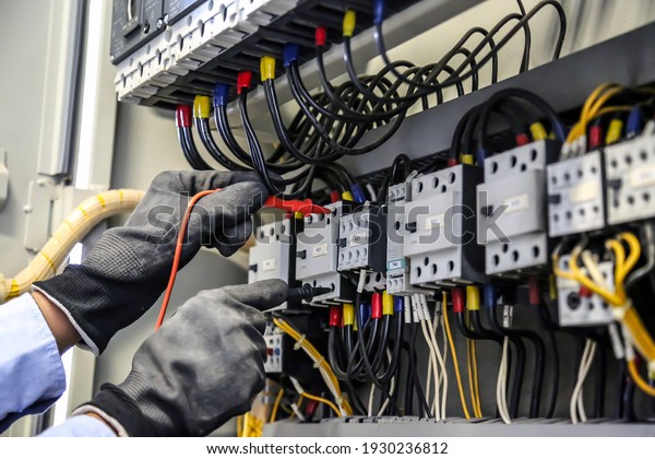 Close-up\
hand of electrical engineering using measuring equipment tool to\
checking electricity at circuit breaker and cable wiring system for\
maintenance in main power distribution\
board.