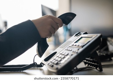 Close-up of the hand of a female office worker dialing a number on a landline phone. Faceless woman secretary calls on the phone - Powered by Shutterstock