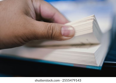 Close-up of a hand flipping through the pages of a book, symbolizing knowledge, education, and the joy of reading. Perfect for concepts related to learning, literature, and curiosity. - Powered by Shutterstock